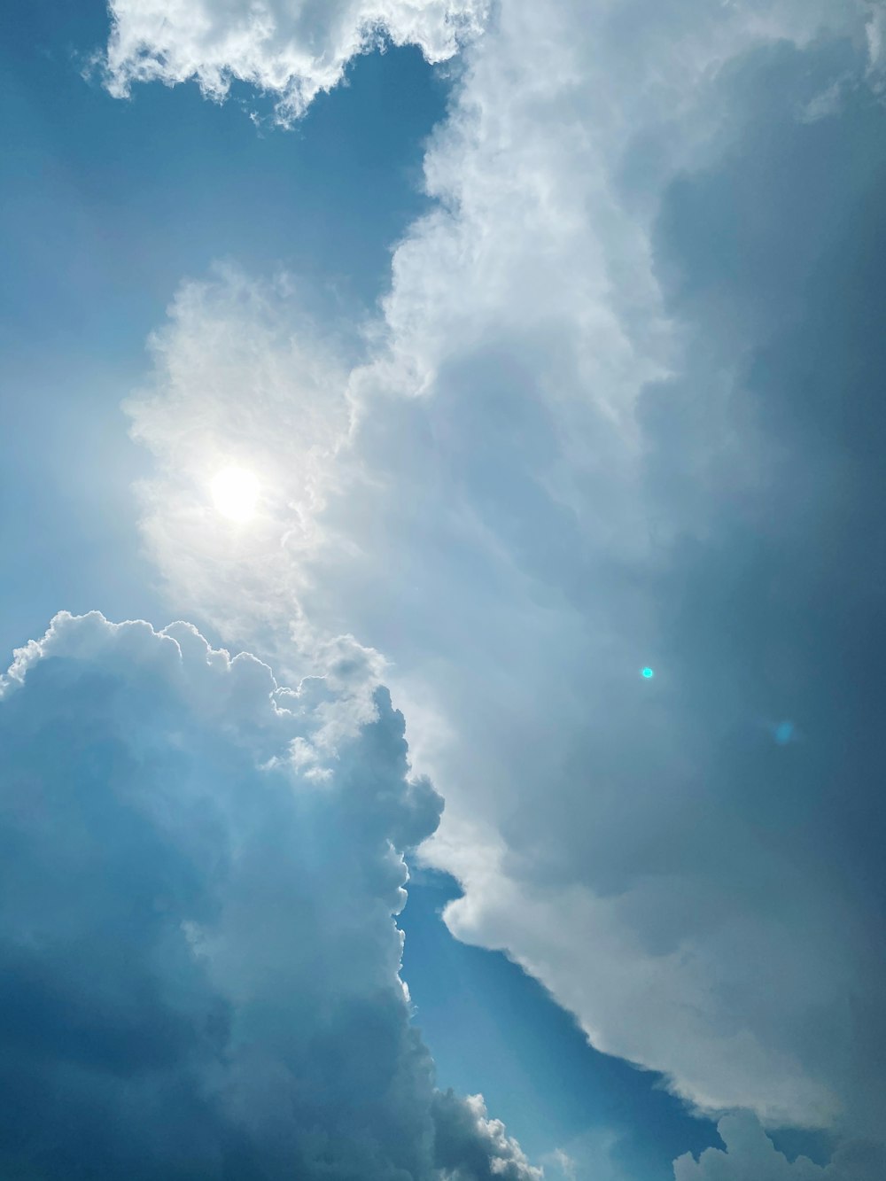 a plane flying through a cloudy blue sky