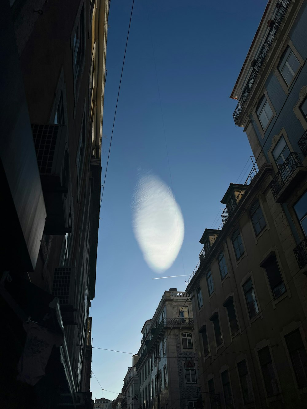 a street view of buildings and a contrail in the sky