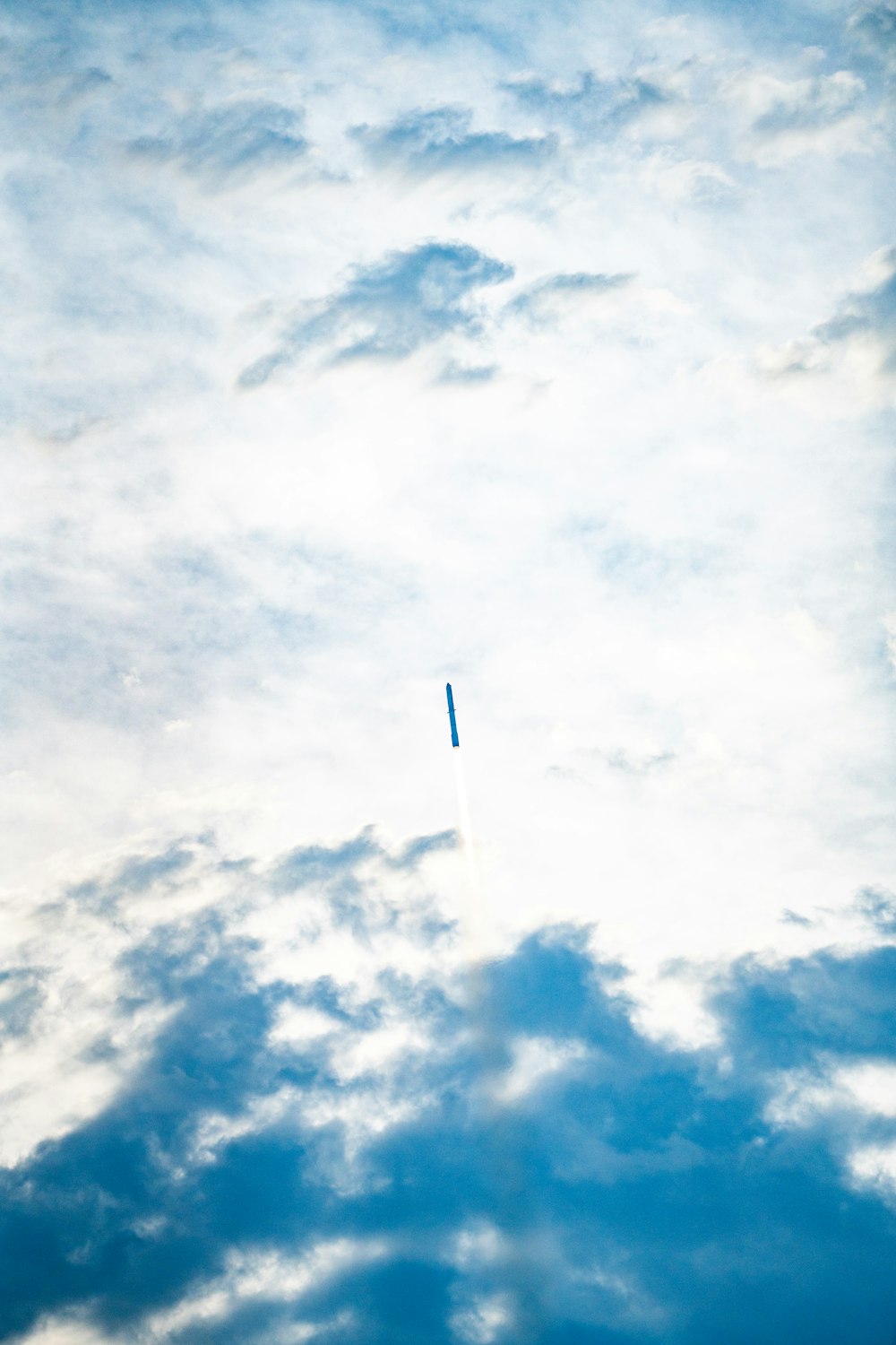 a plane flying through a cloudy blue sky