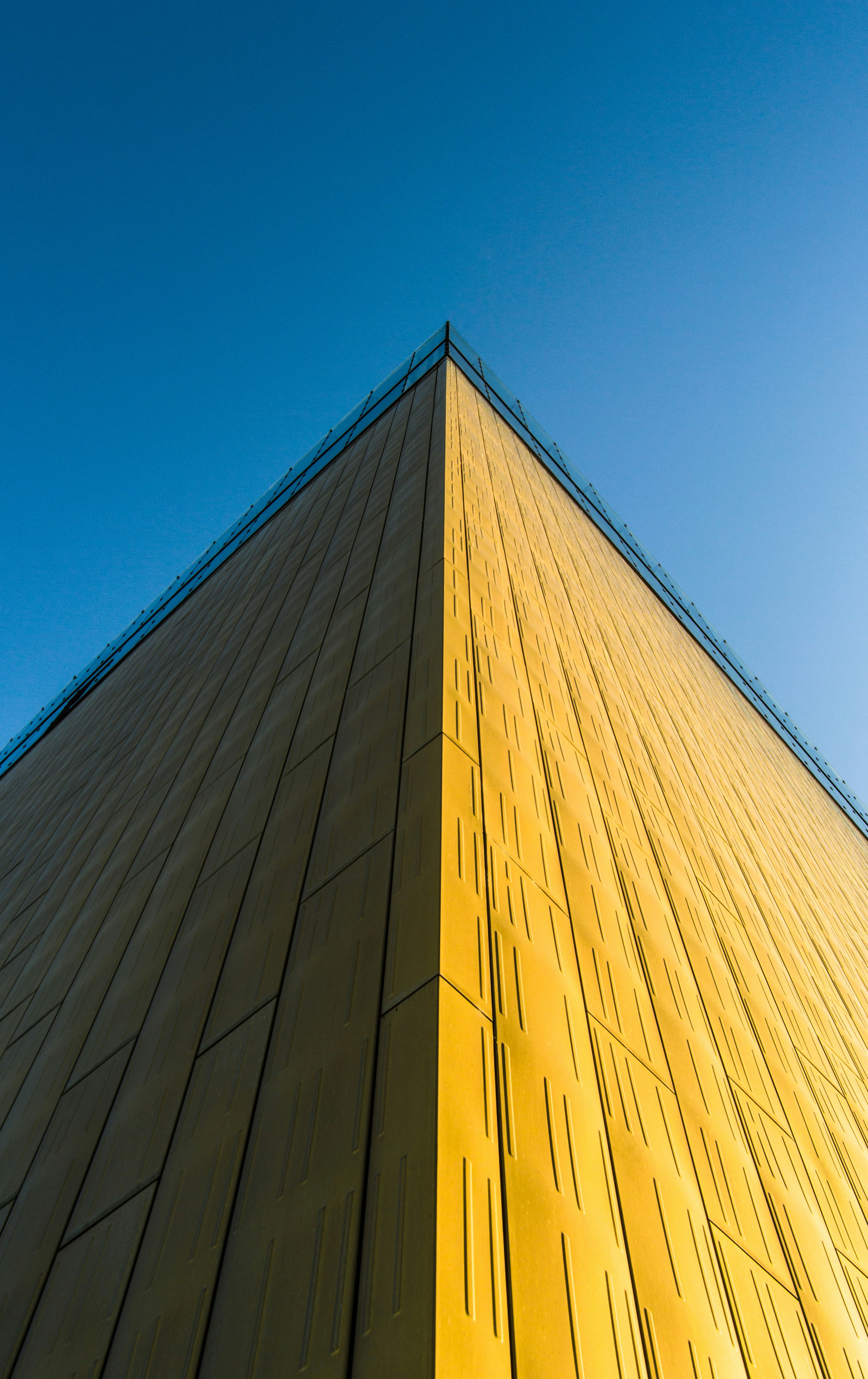 a tall yellow building with a blue sky in the background