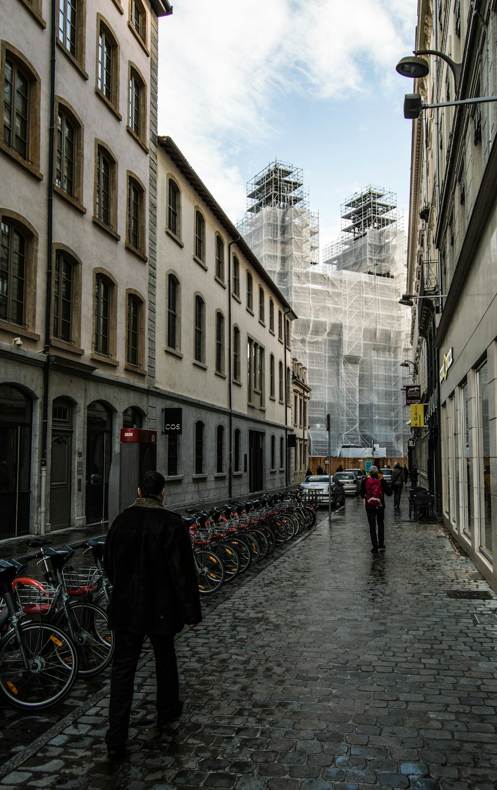 a man walking down a street next to tall buildings