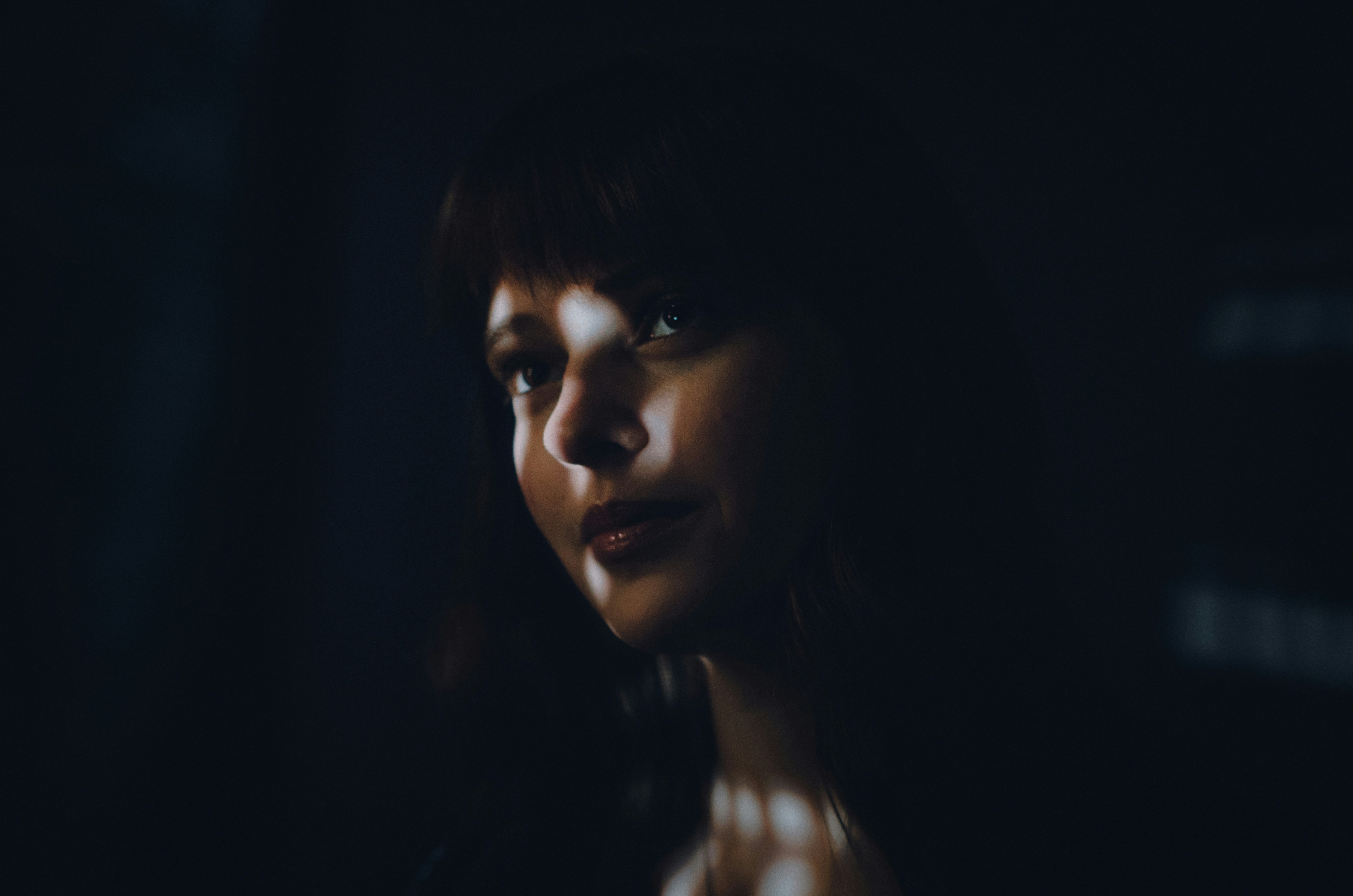 Woman in a dark room looking off into the distance