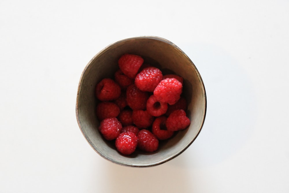 a bowl of raspberries on a white table