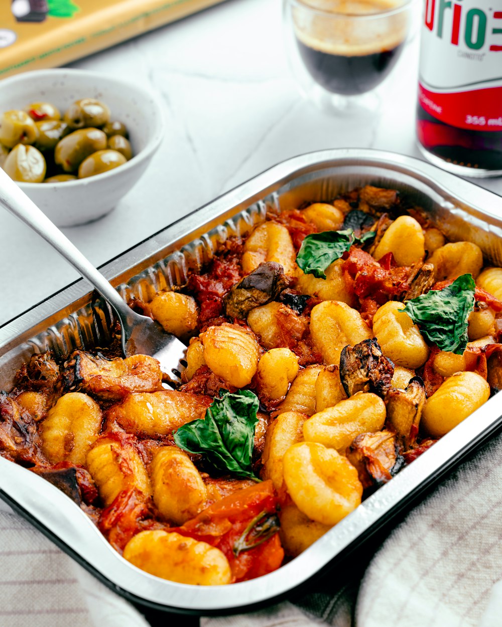 a dish of pasta with spinach and olives