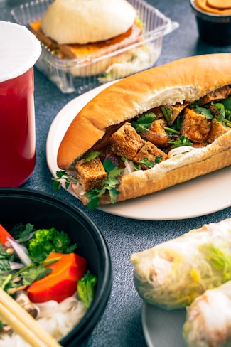 a sandwich on a plate next to a bowl of salad