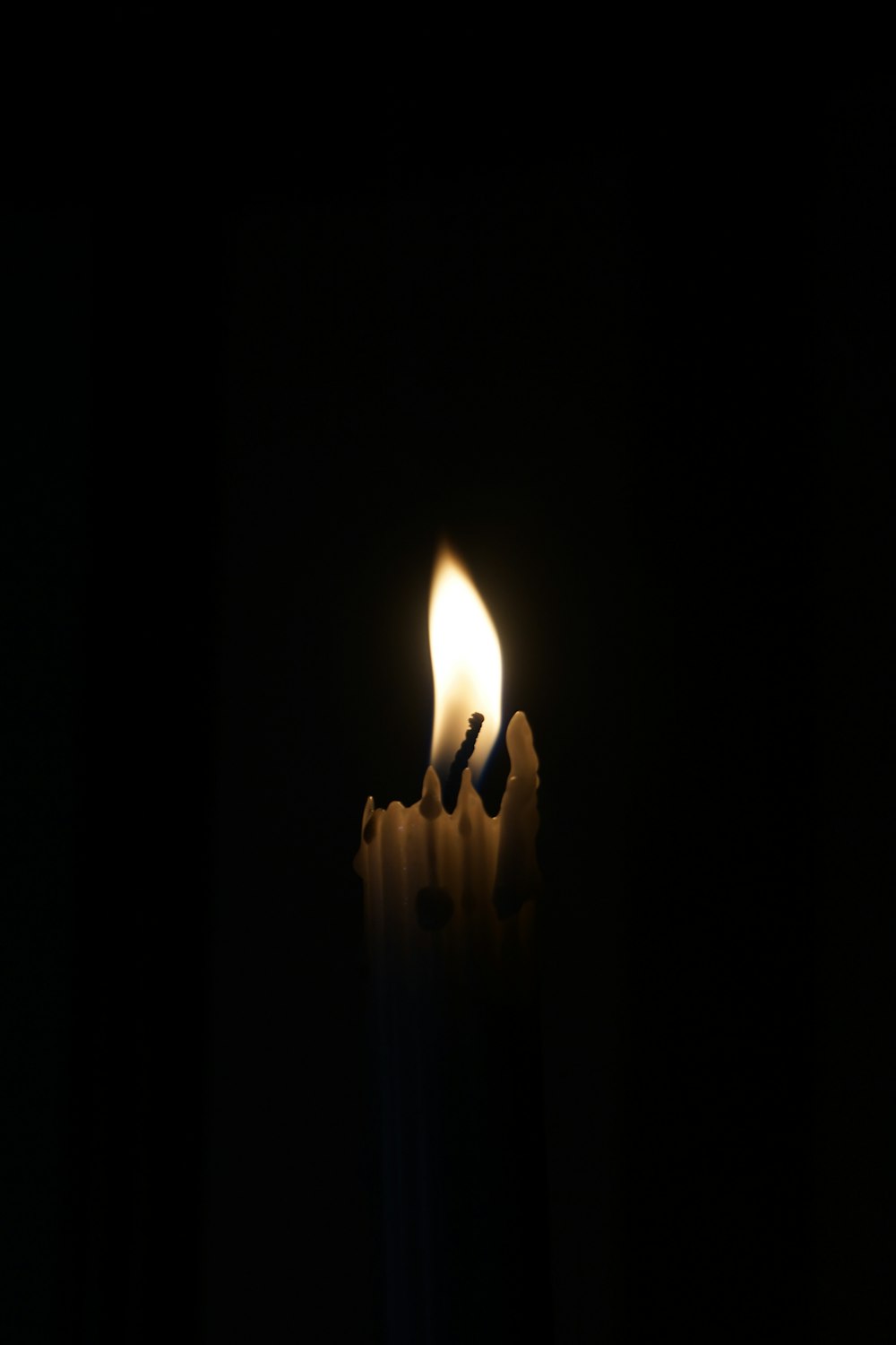 a lit candle in the dark with a black background