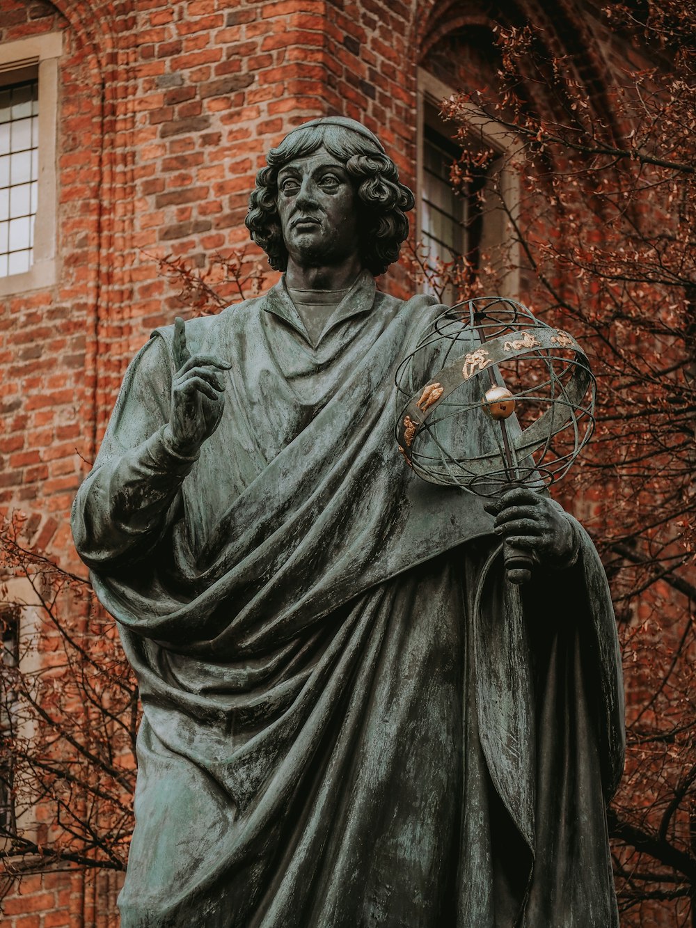a statue of a man holding a fan in front of a brick building