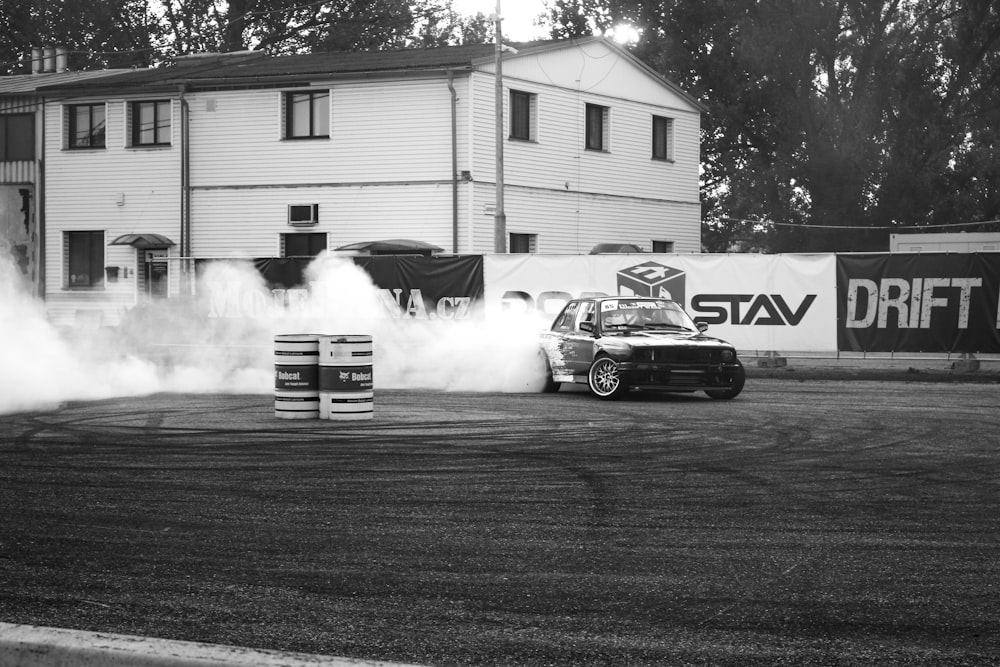 a black and white photo of a car kicking up smoke