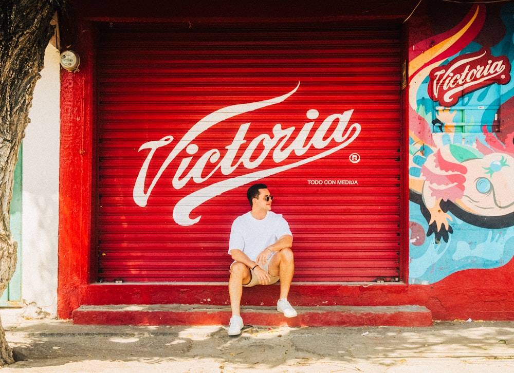 a man sitting on a bench in front of a red door