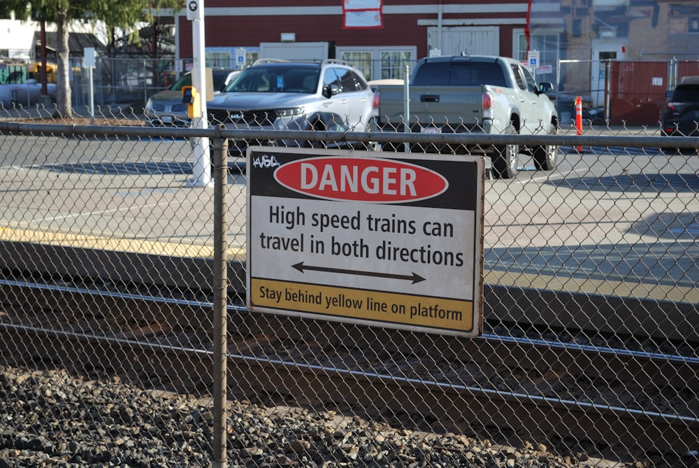 a sign on a chain link fence warning of high speed trains