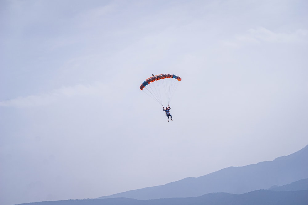 a person is parasailing in the sky with mountains in the background