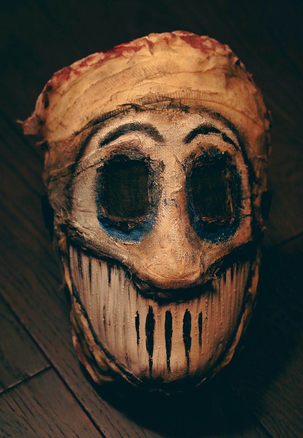 uma máscara assustadora em um chão de madeira