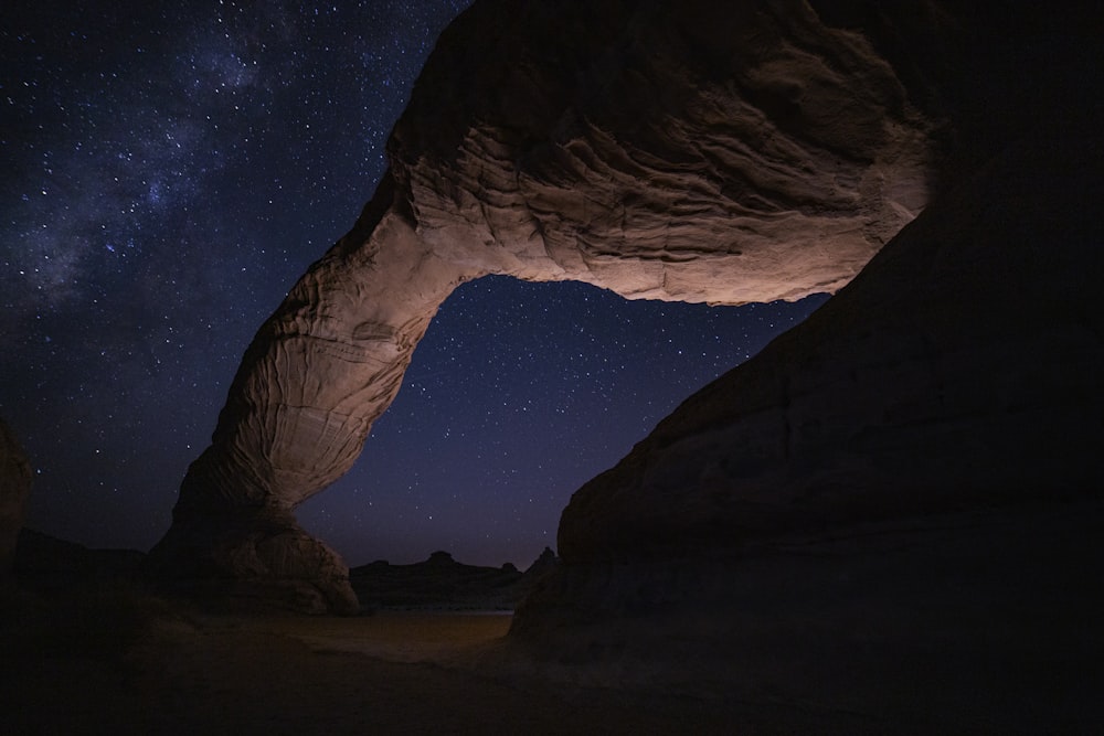 Una grande formazione rocciosa con un cielo pieno di stelle sullo sfondo