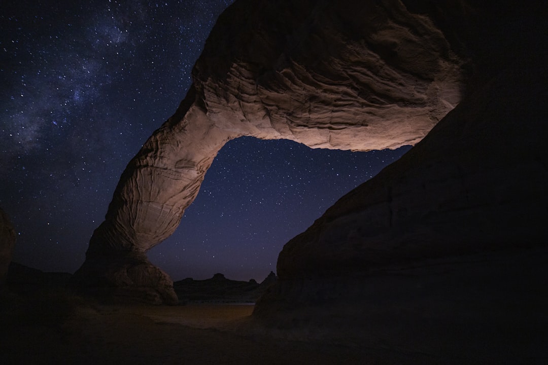 a large rock formation with a sky full of stars in the background, Al-Ula