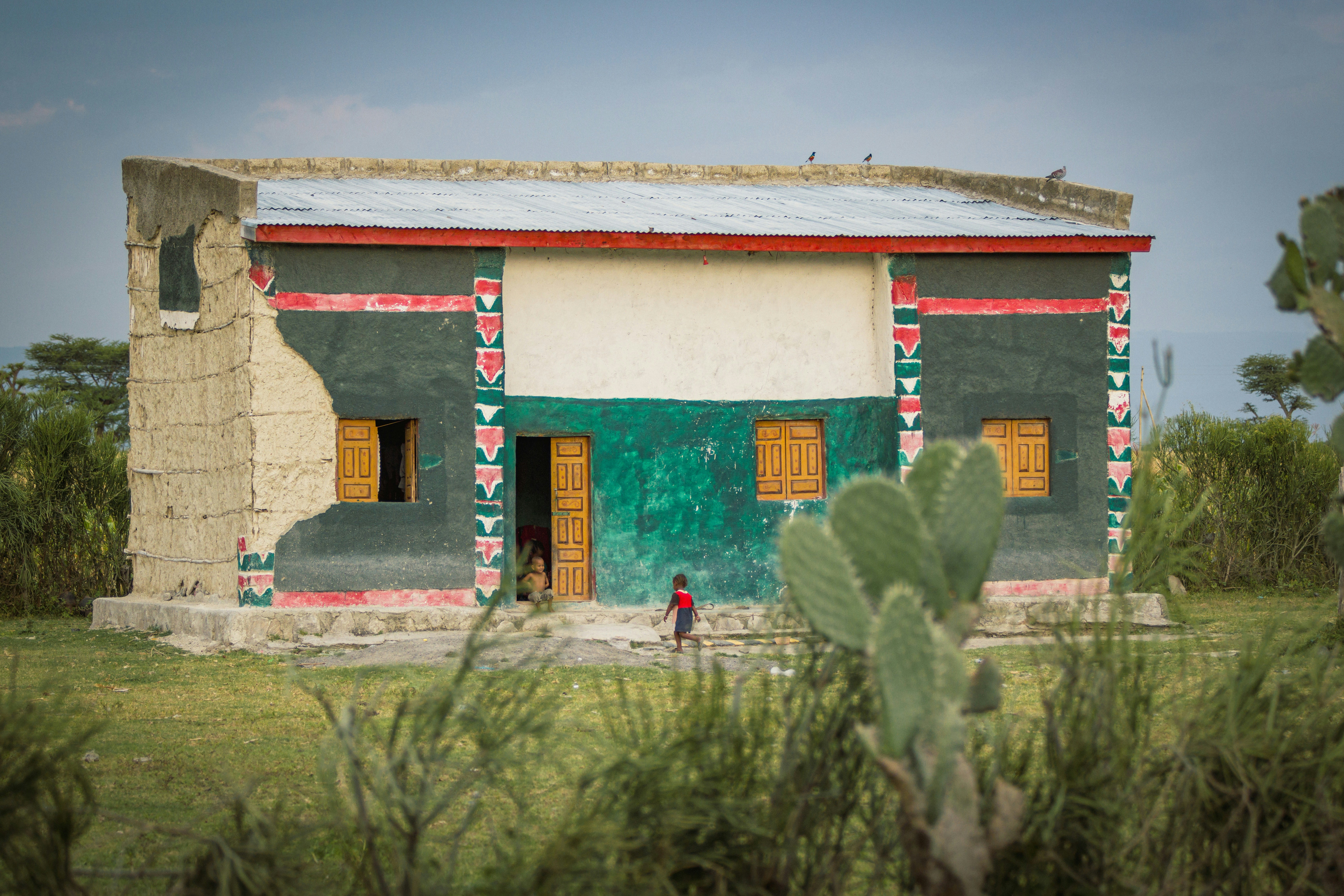 Completed school building in a developing country, with children happily entering and playing, showcasing the long-term impact of Sadaqah Jariyah on education - how to give sadaqah