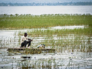 a man sitting on a small boat in a body of water