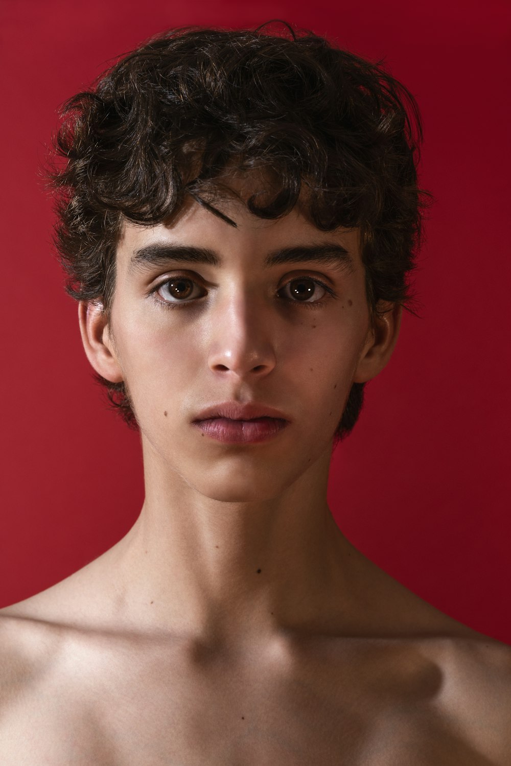 a young man with curly hair and no shirt