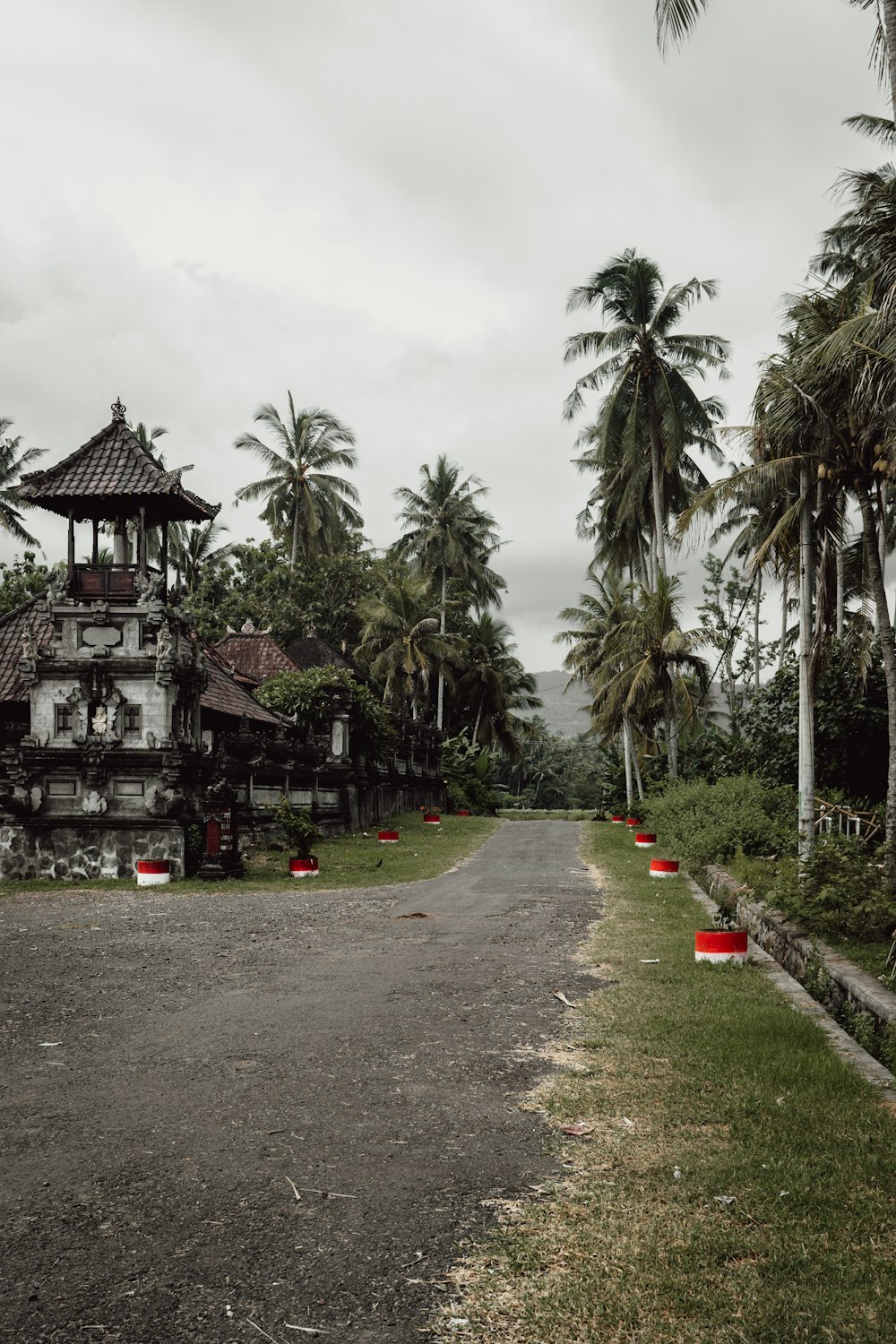 an old house in the middle of a road surrounded by palm trees
