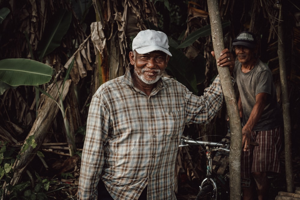 a man standing next to a tree next to a bike