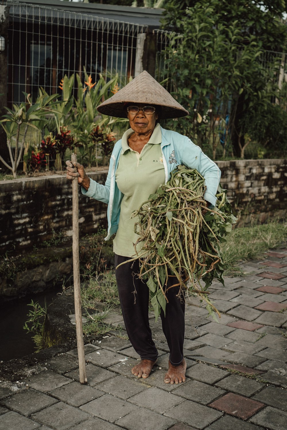 eine Frau mit einem Stock und einem Strauß Pflanzen