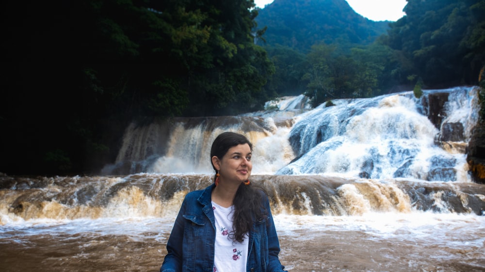 a woman standing in front of a waterfall