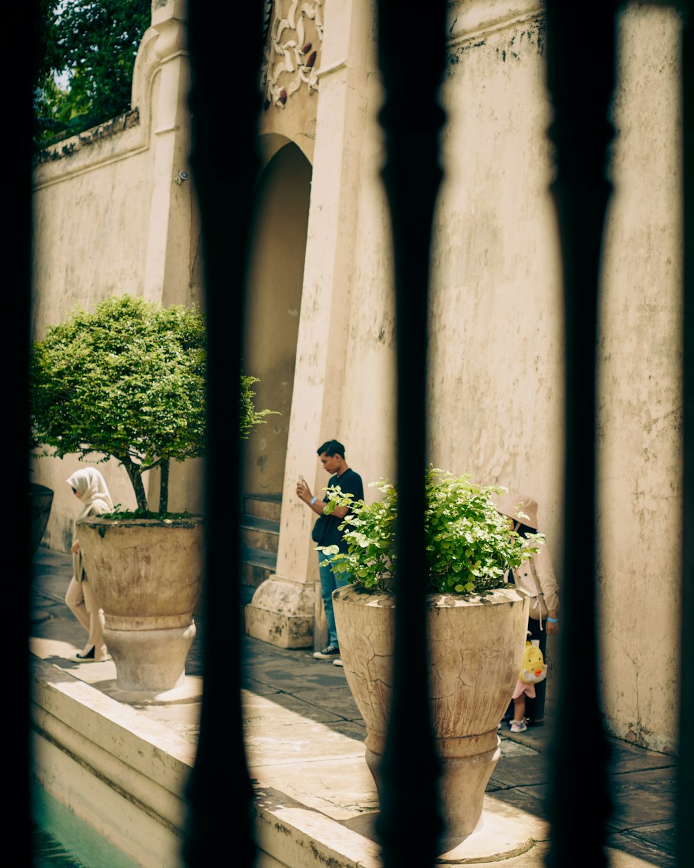 a man sitting on a bench next to a tall planter