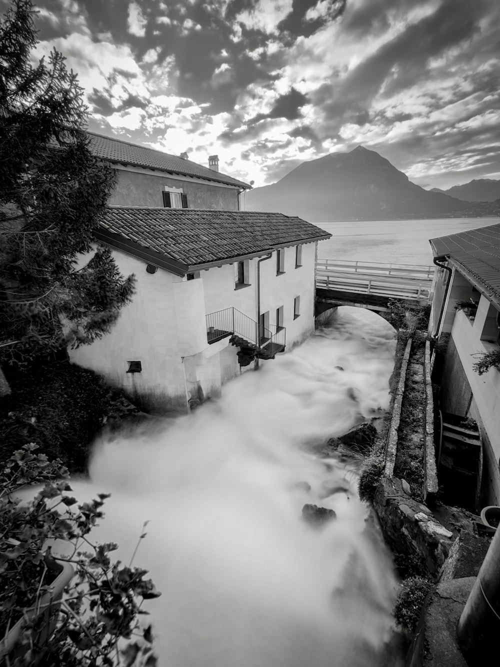 a black and white photo of a river running through a town
