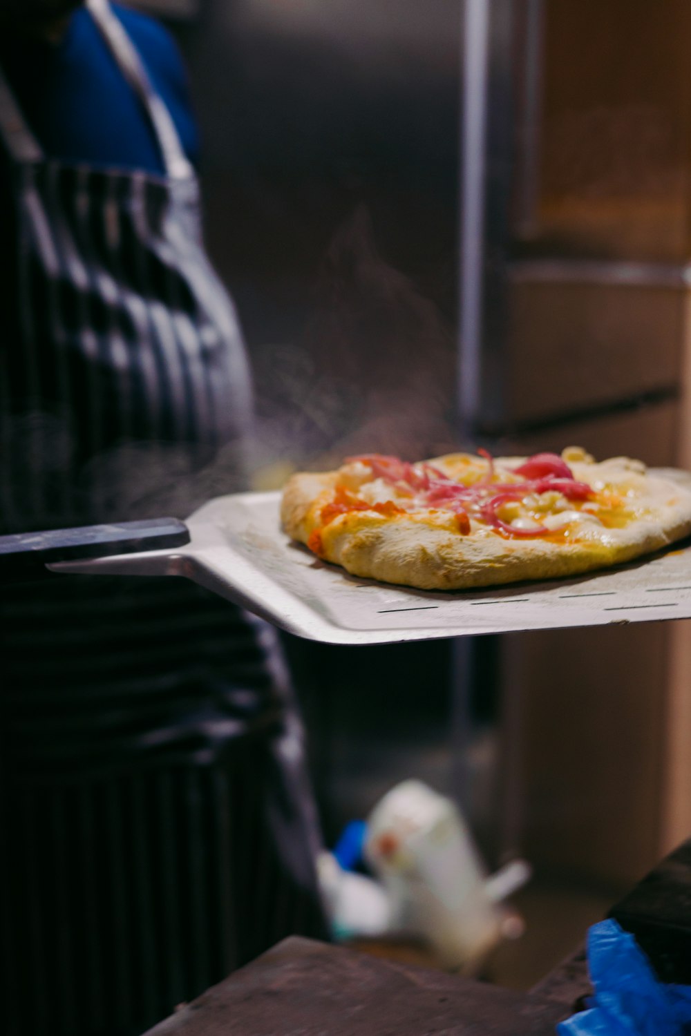 a person holding a tray with a pizza on it