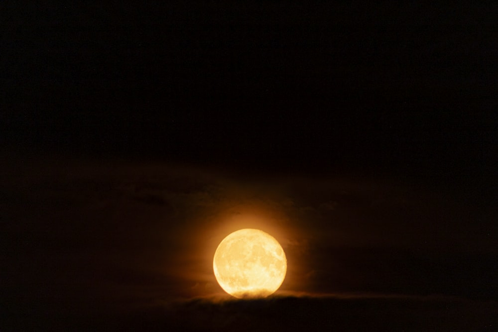 a full moon seen through the clouds in the night sky