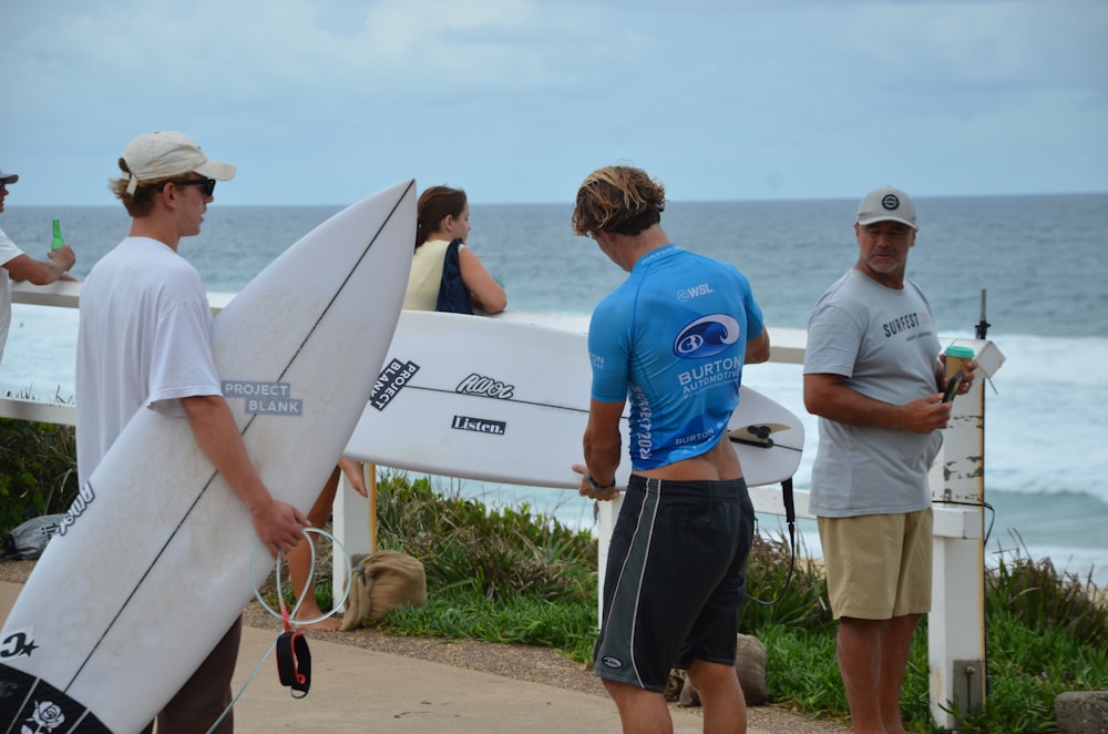 a group of people holding surfboards near the ocean