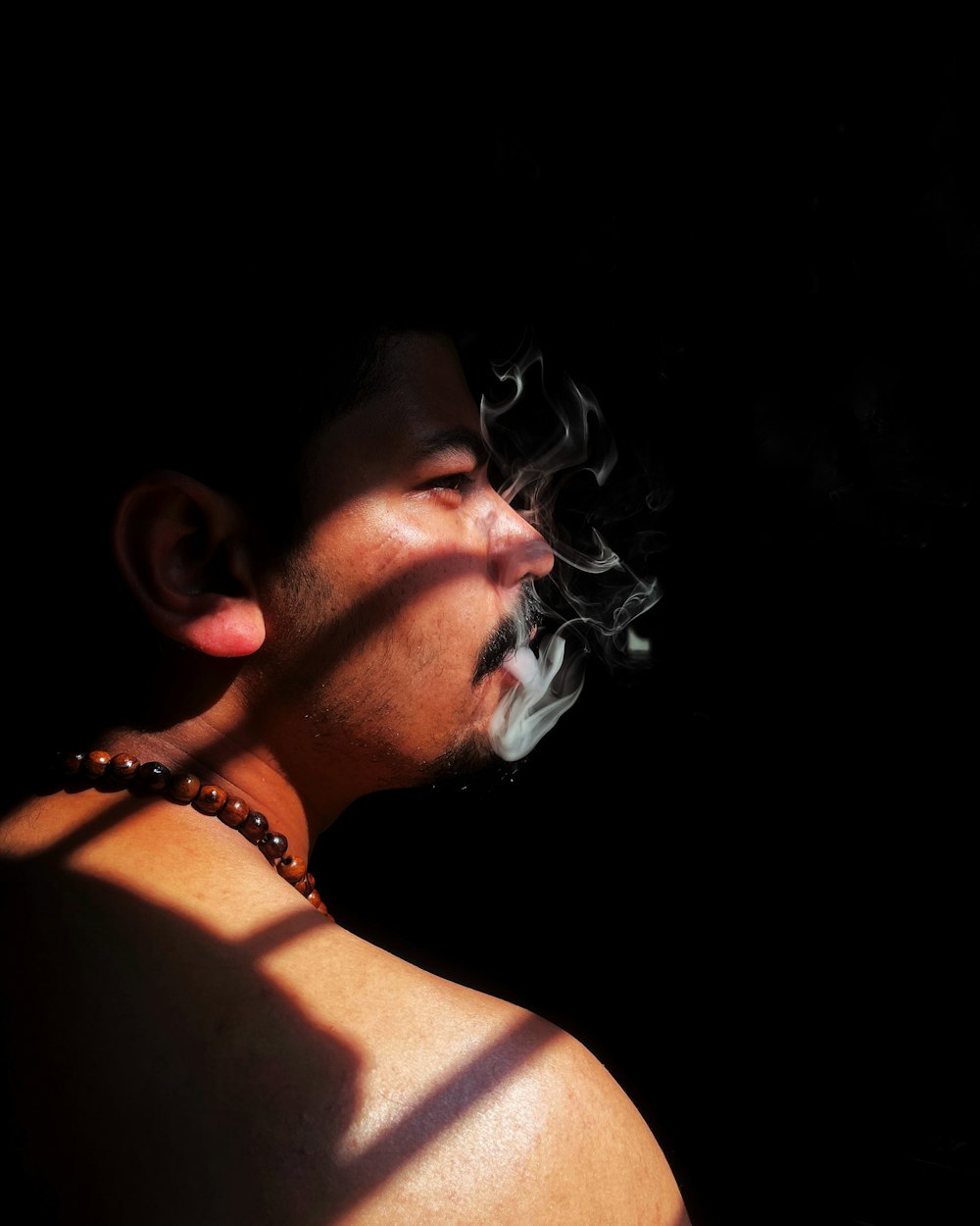 a man smoking a cigarette in the dark