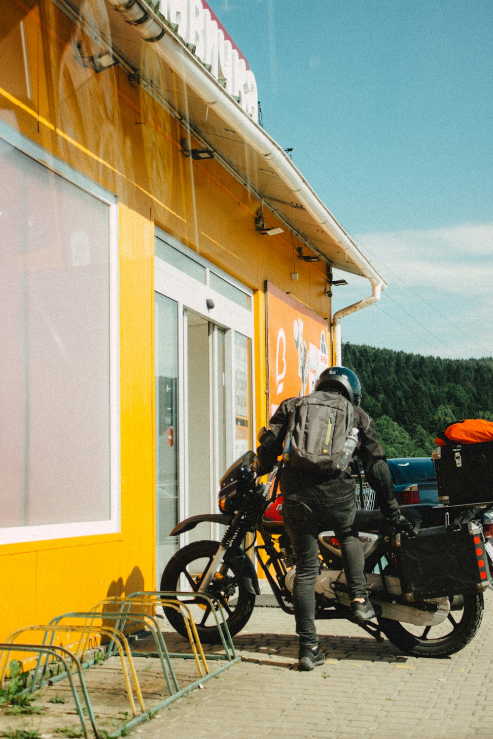 a man riding a motorcycle next to a yellow building