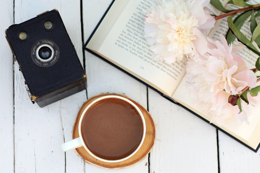 una taza de café junto a un libro abierto