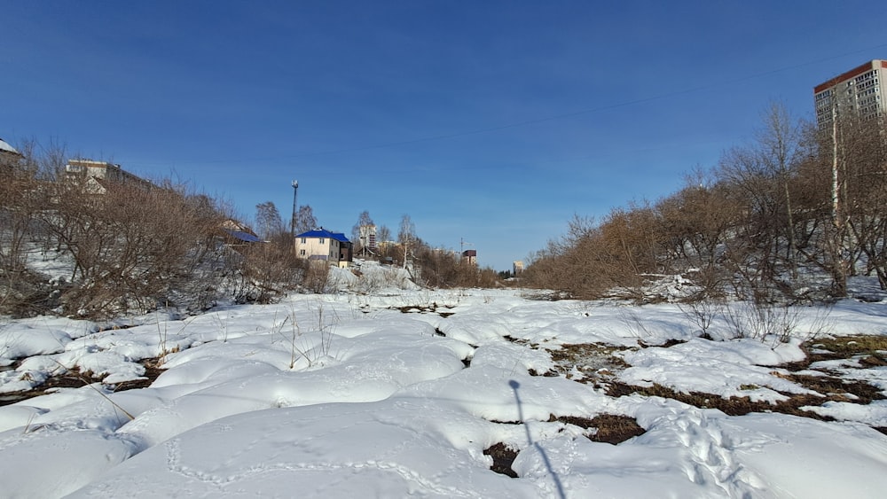 a snow covered field with buildings in the background