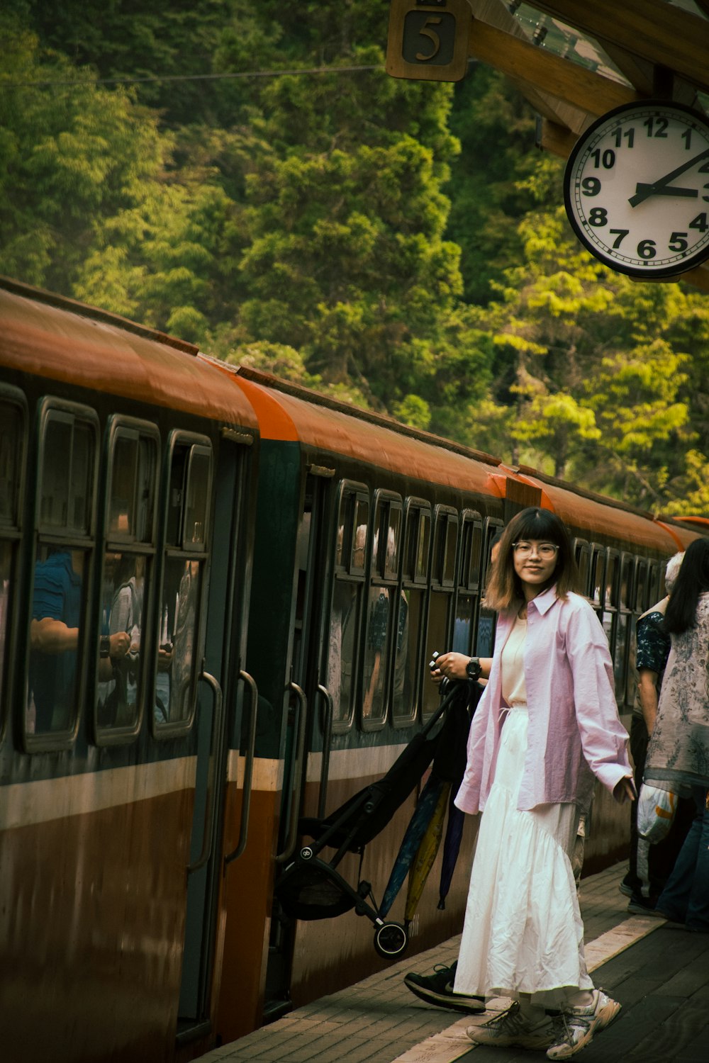 Eine Frau in einem langen weißen Kleid steht neben einem Zug