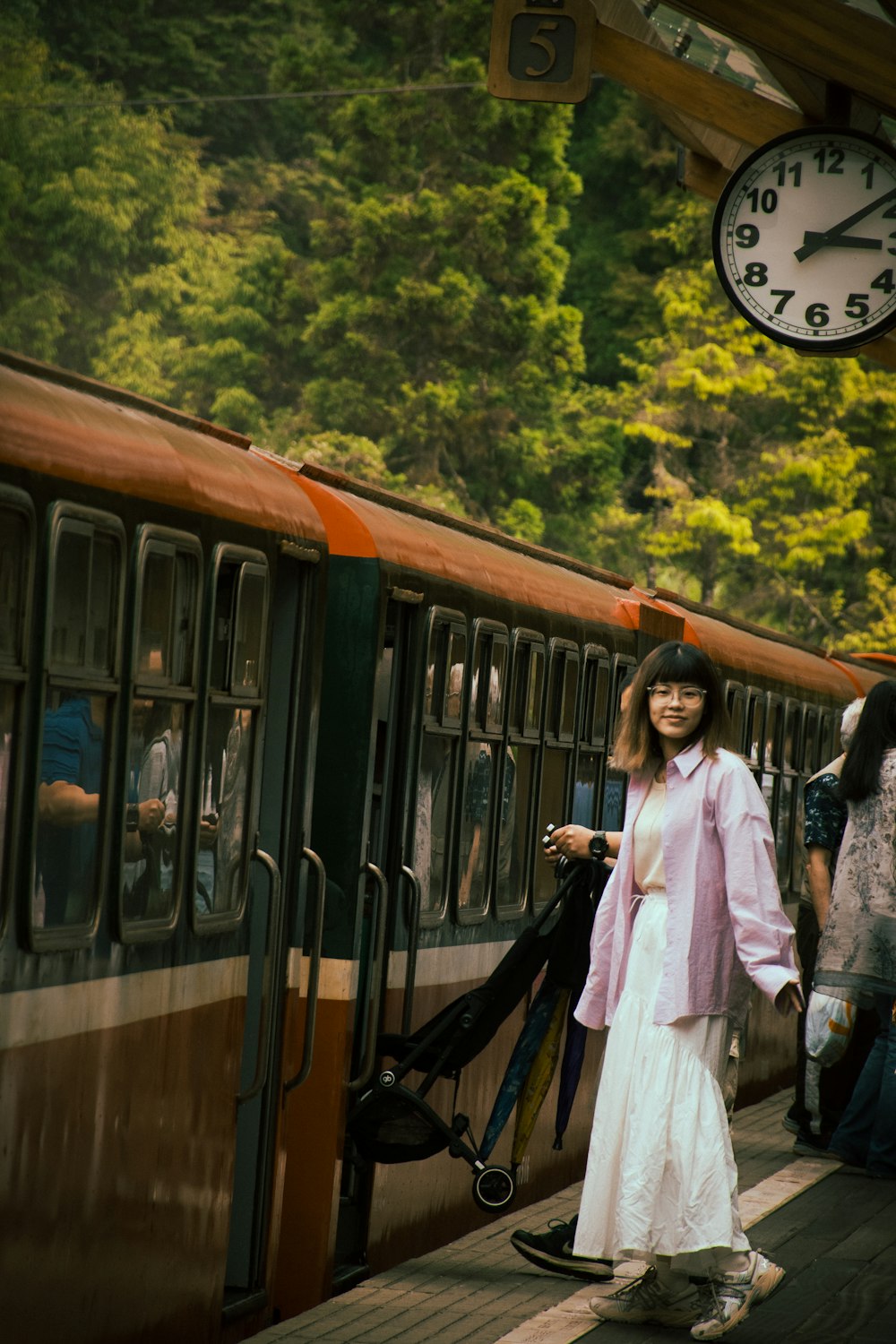 a woman in a long white dress standing next to a train