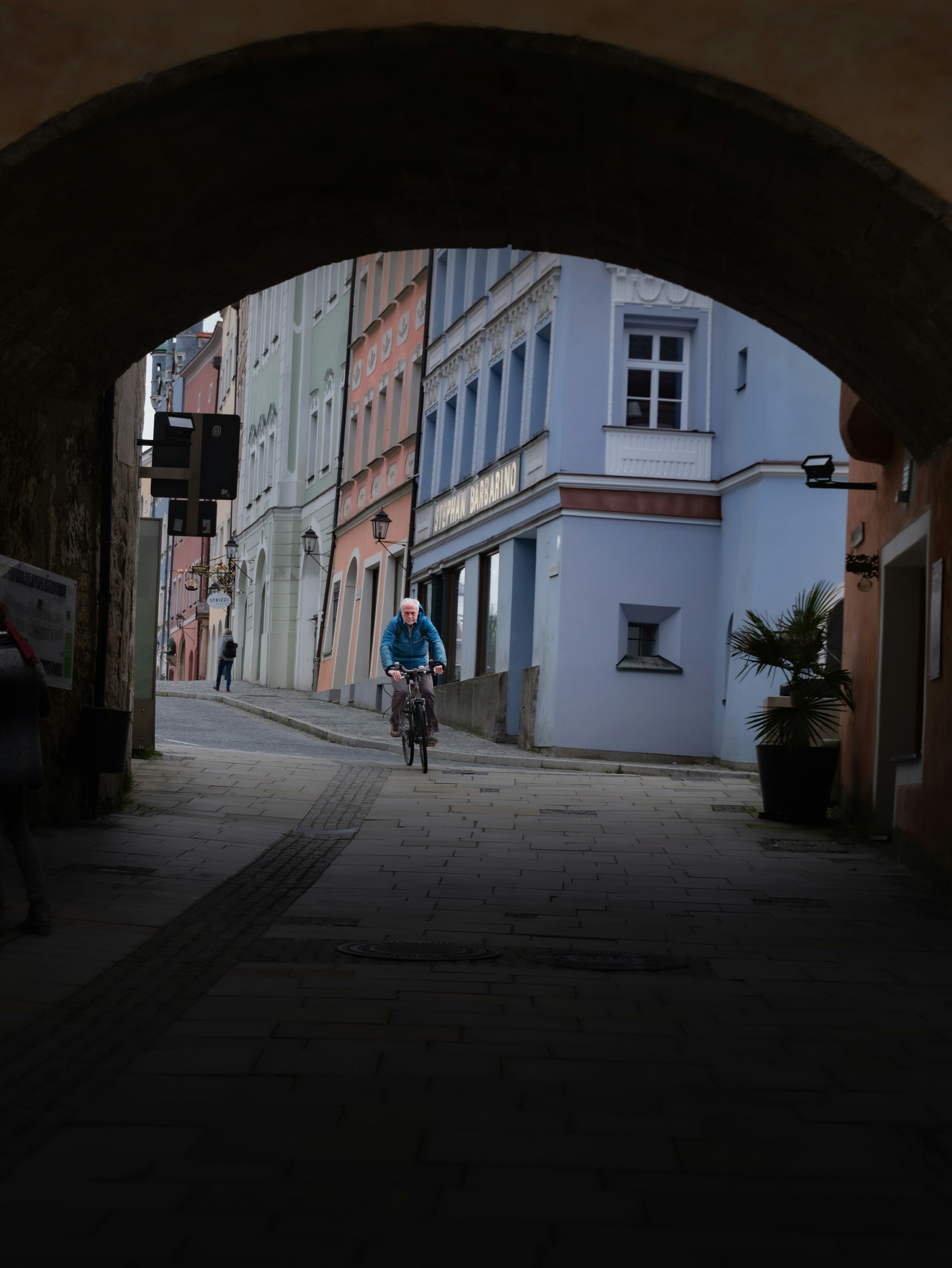 a man riding a bike down a street under a bridge