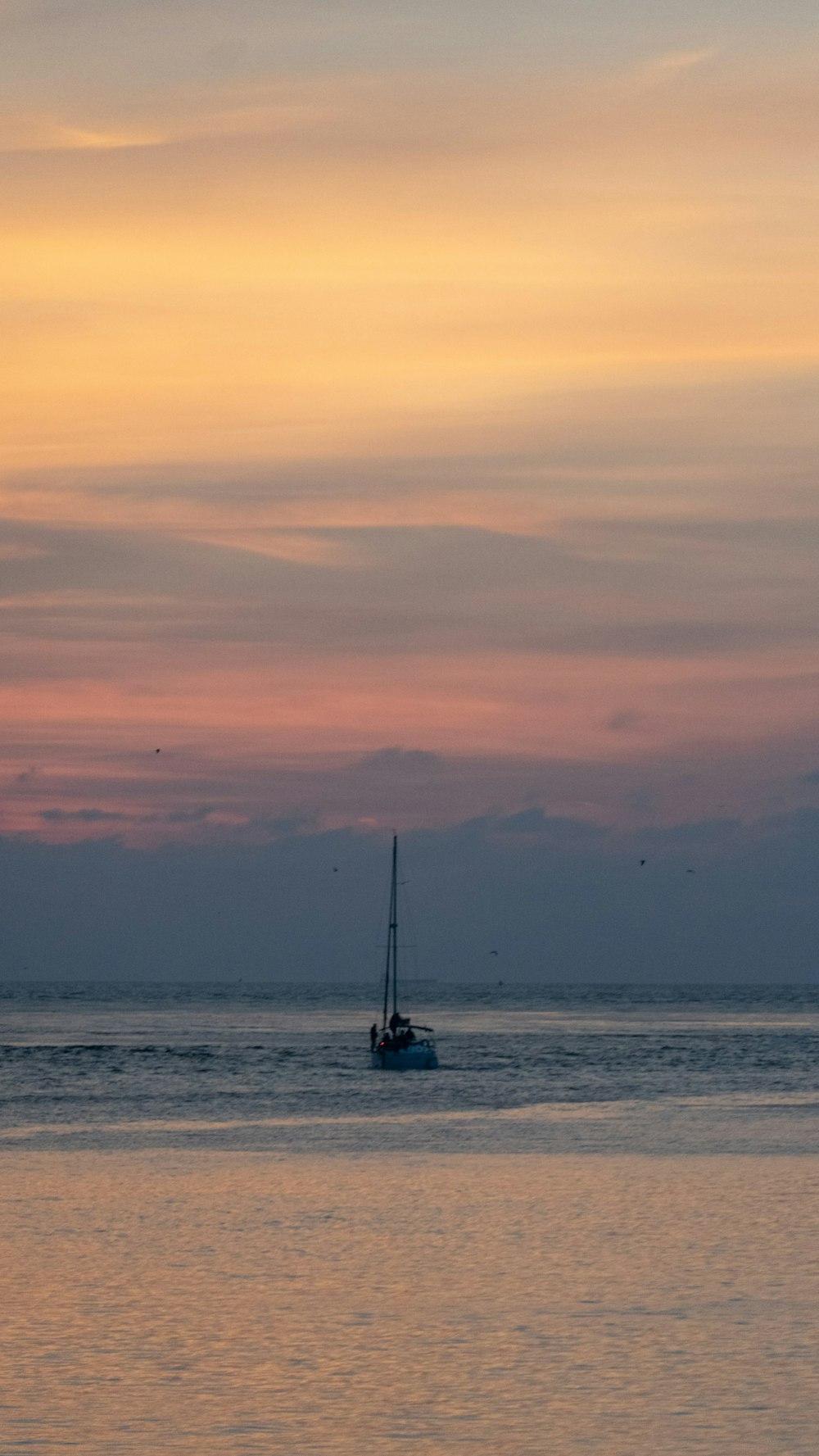 a sailboat floating in the ocean at sunset