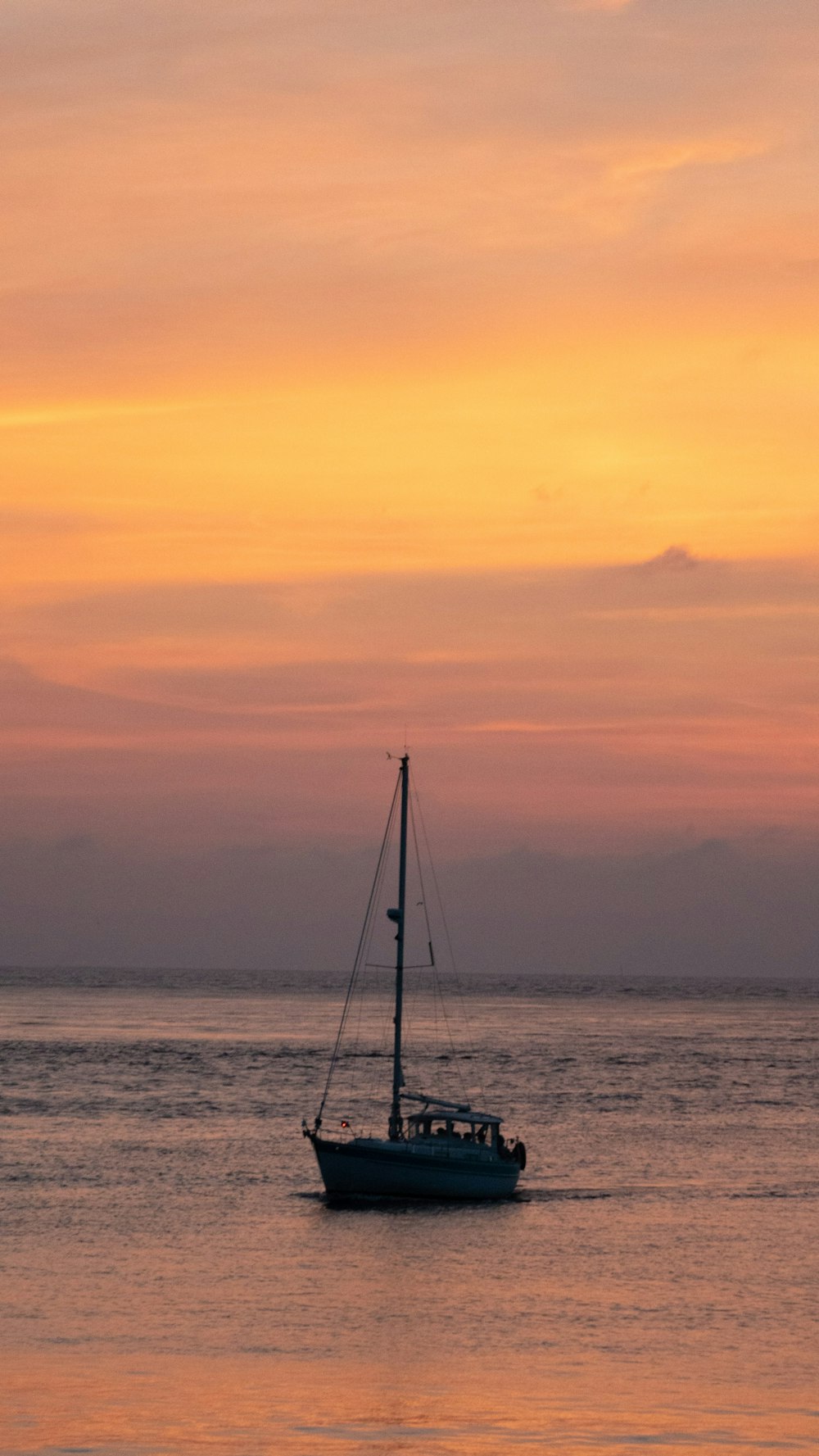 a sailboat floating in the ocean at sunset