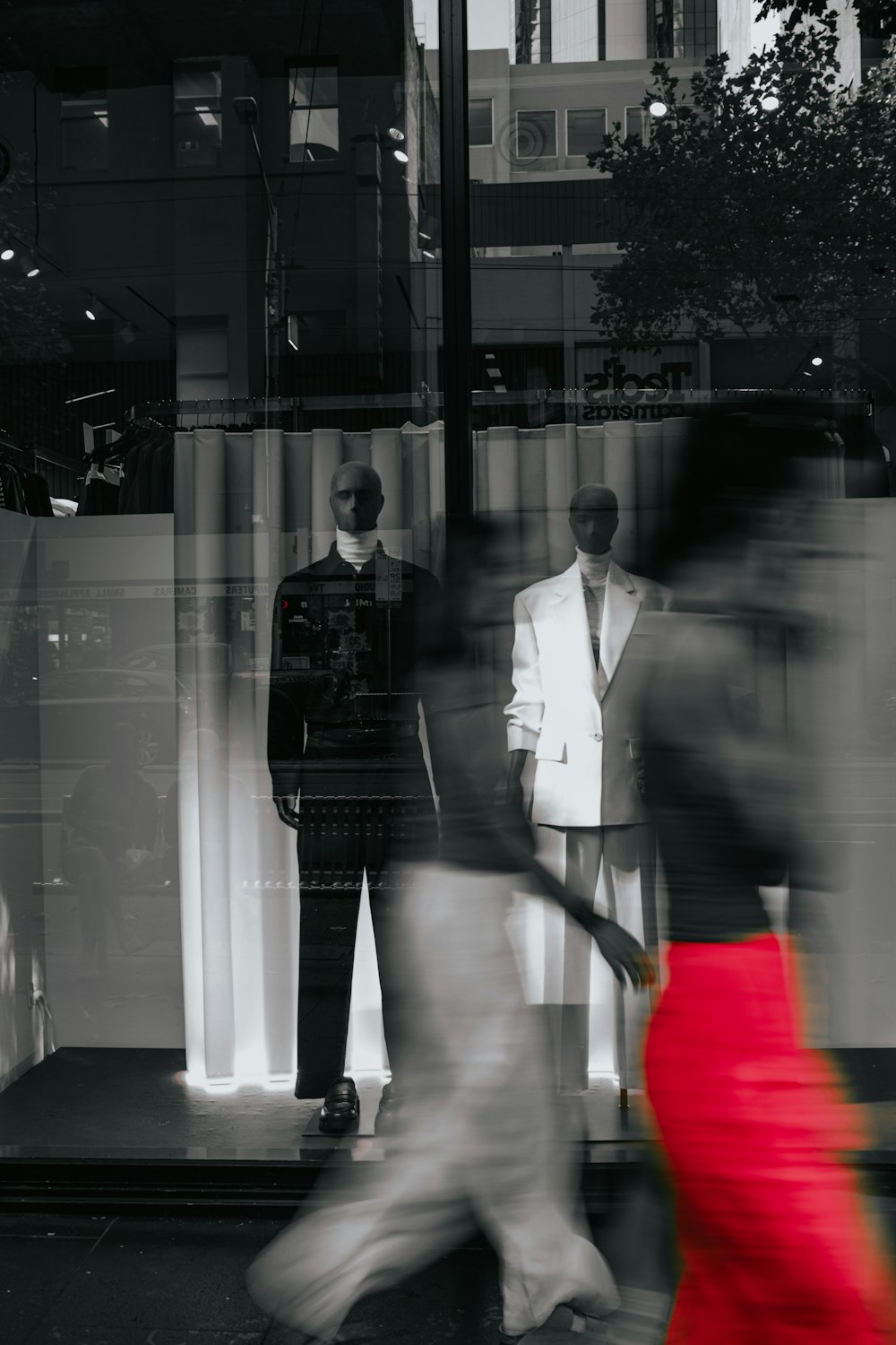 a woman in a red dress walking past a store window