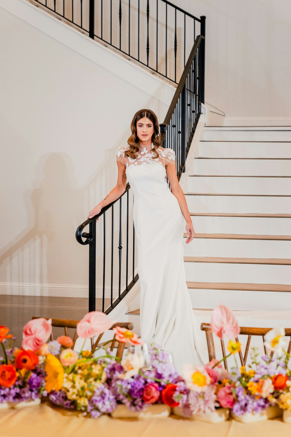 a woman in a white dress standing in front of a staircase