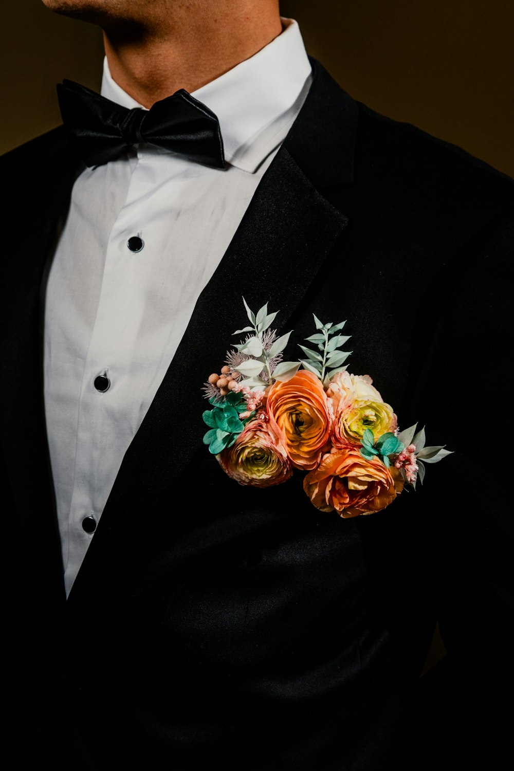 襟に花を飾るタキシード姿の男性