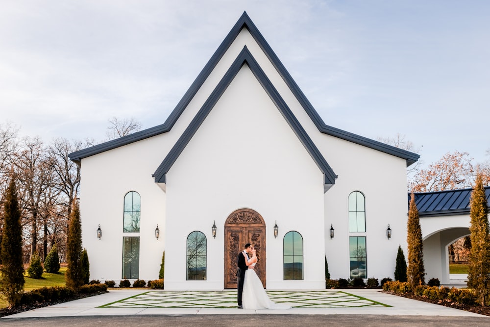 a bride and groom standing in front of a church