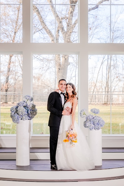 a bride and groom standing in front of a large window