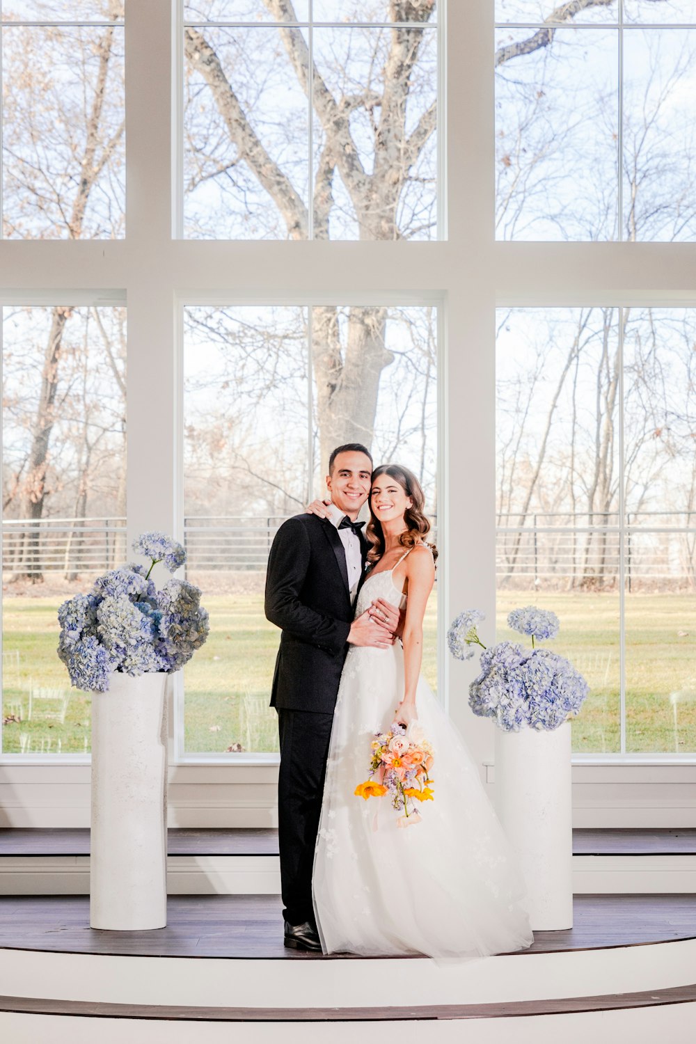 a bride and groom standing in front of a large window