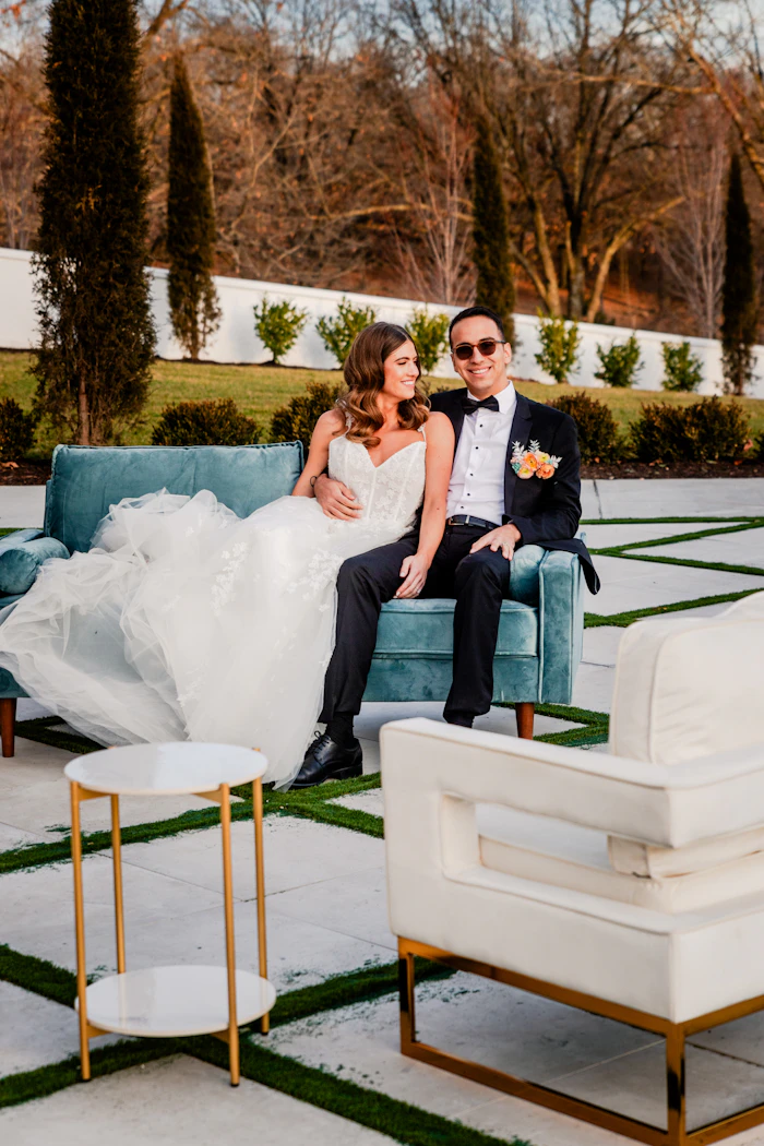 Pareja de novios sentada en un sillón de terciopelo verde