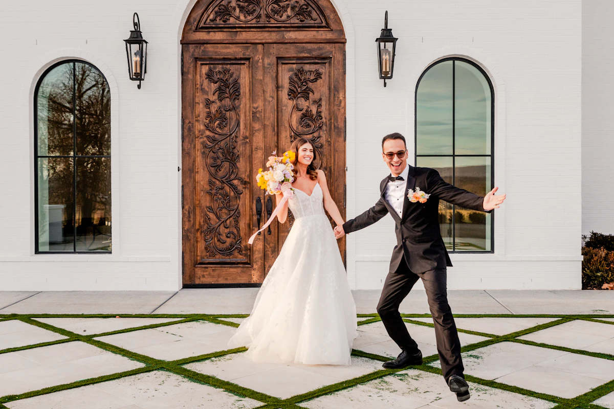 Recién casados bailando frente a la puerta de madera de la hacienda