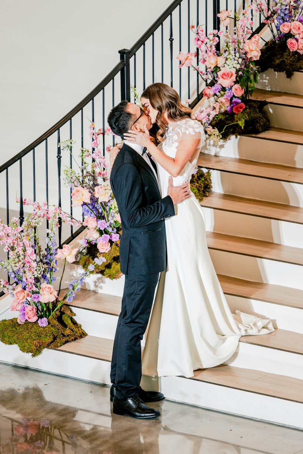 a bride and groom kissing in front of a staircase