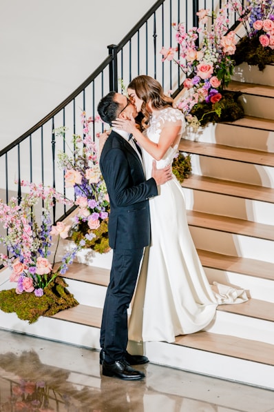 a bride and groom kissing in front of a staircase