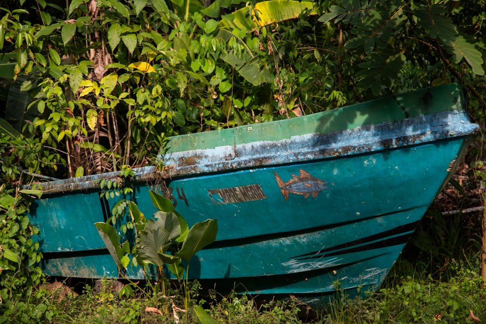 a blue boat sitting on top of a lush green field